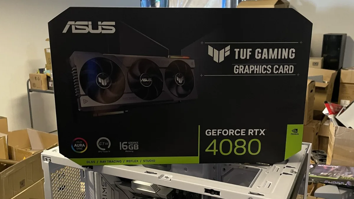 Box of an ASUS TUF Gaming GeForce RTX 4080 graphics card next to a gaming PC case in the FlowUP workshop