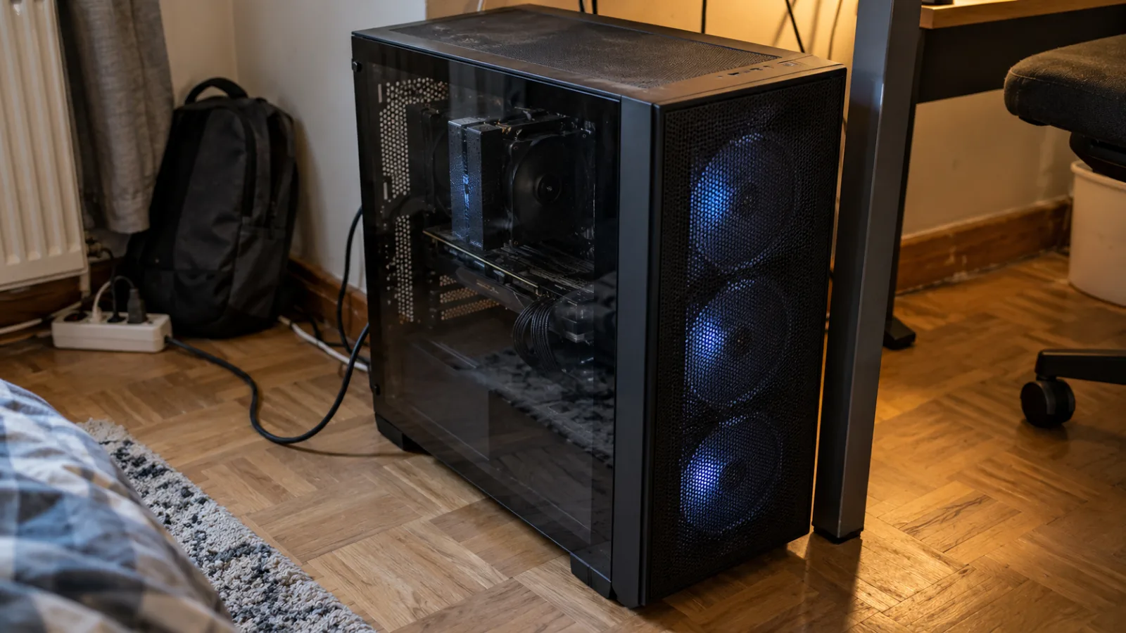Zwarte mid-tower op de vloer, naast een bureau