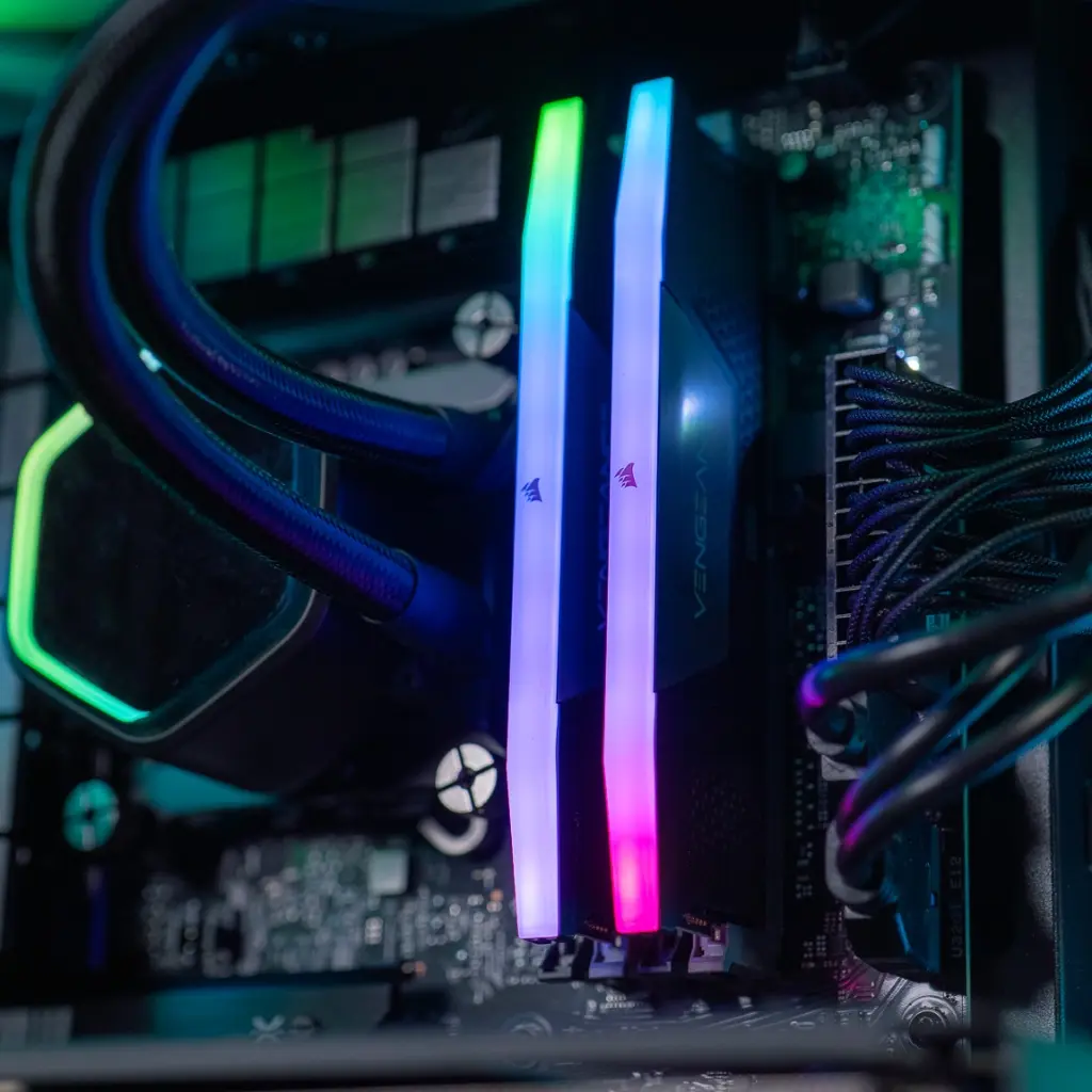Gros plan sur les barrettes de RAM Corsair Vengeance DDR5 avec un éclairage ARGB dégradé, installées à côté du waterblock Cooler Master dans le PC gamer Aqua