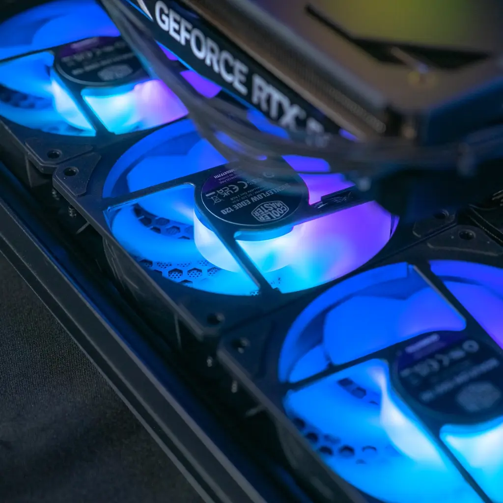 Gros plan sur la base du boîtier FlowUP H600 Aquavision du PC gamer Aqua montrant les trois ventilateurs avec leur éclairage ARGB bleu et violet