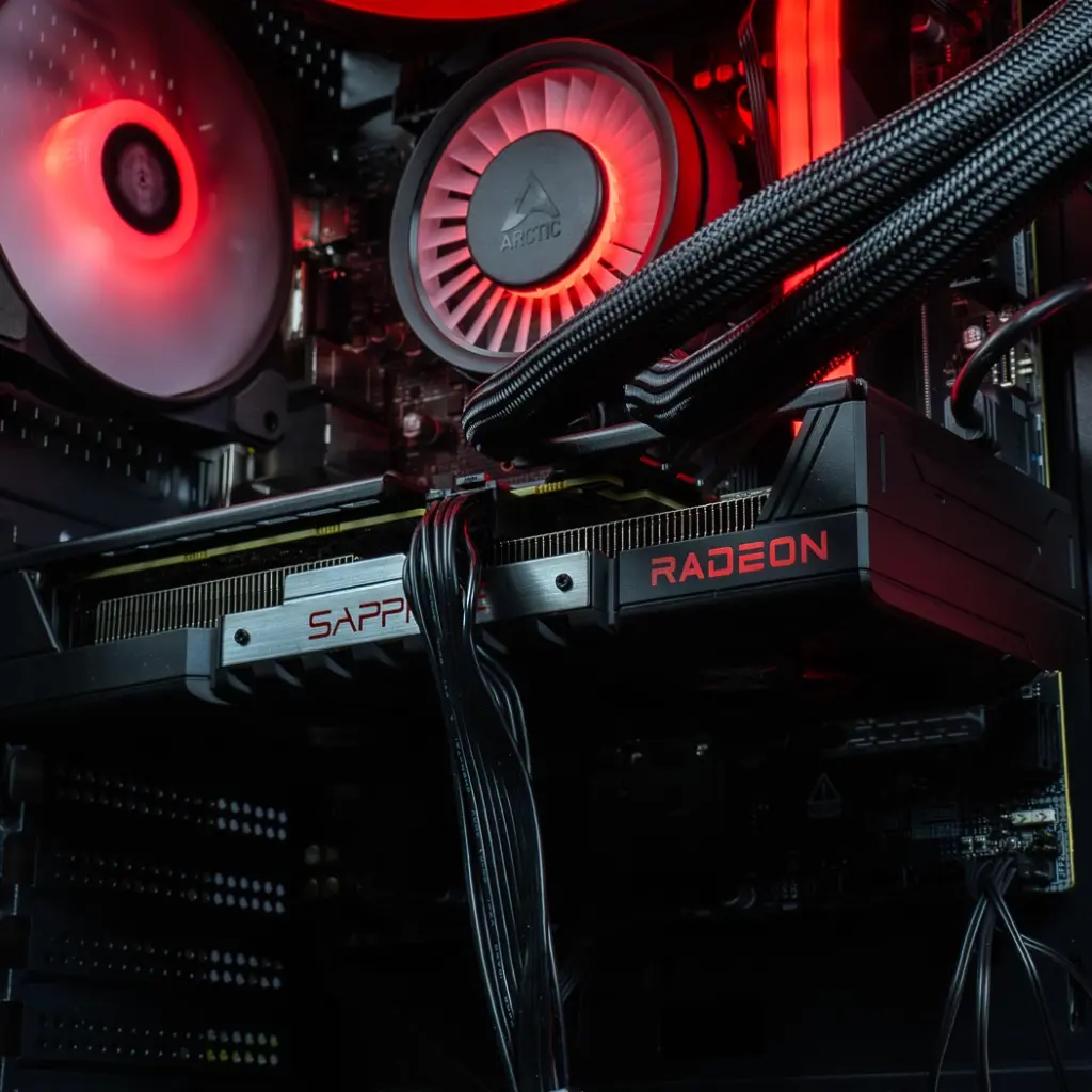 Gros plan sur la carte graphique Sapphire Radeon installée dans le PC gamer Rift RX 9060 XT, avec son logo rétroéclairé en rouge et ses caloducs visibles au-dessus du ventilateur arrière