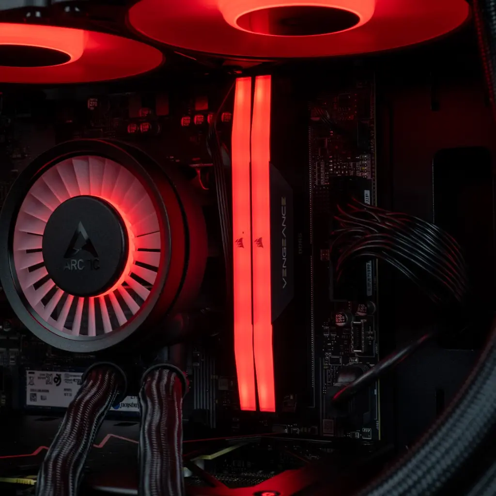 Gros plan sur les deux barrettes de mémoire vive Corsair Vengeance DDR5 rétroéclairées en rouge, installées à côté du waterblock Arctic dans le PC Rift RX 9060 XT