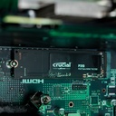 Gros plan sur le SSD NVMe Kingston NV2 de 1 To installé sur la carte mère du PC Rift RX 9060 XT, situé juste en dessous du waterblock Arctic Liquid Freezer III éclairé en rouge