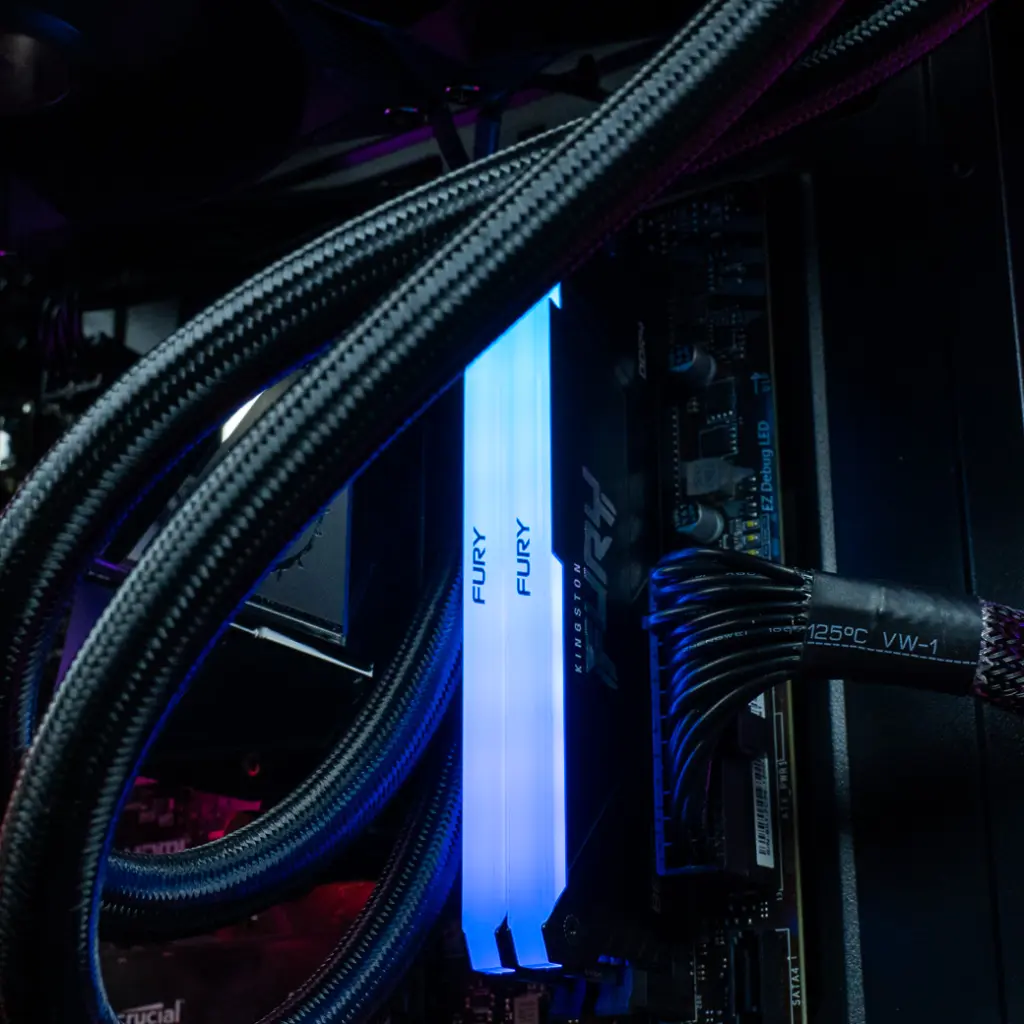 Vue rapprochée des barrettes de mémoire vive Kingston FURY RGB éclairées en bleu à l'intérieur du PC gamer Nightwing