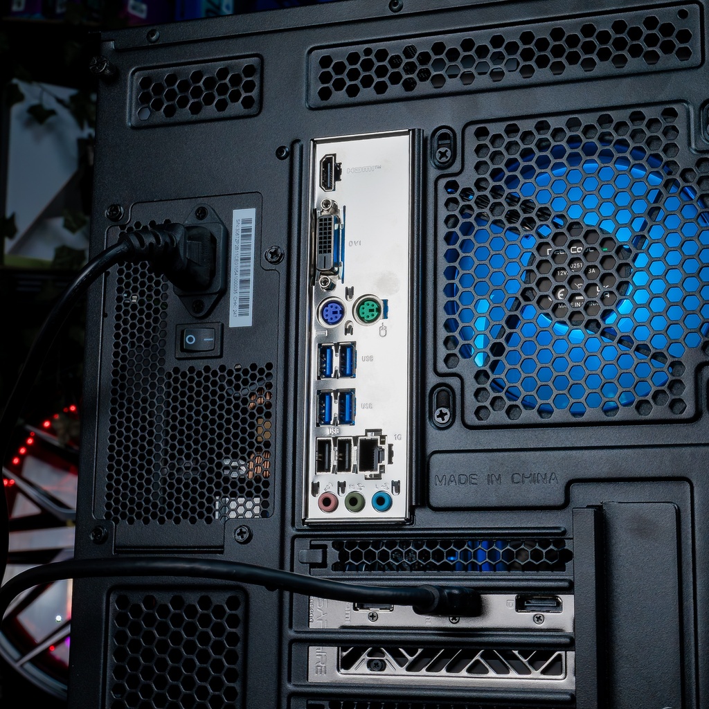 Vue arrière du PC gamer Nightwing mettant en évidence le panneau de connectique complet, l'alimentation avec interrupteur et le ventilateur MSI ARGB bleu à travers la grille en nid d'abeille