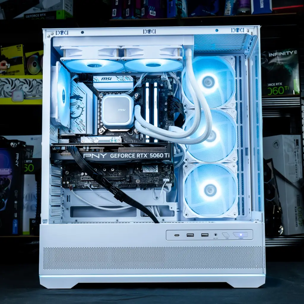 Vue d'ensemble interne du PC gamer Rubis dans son boîtier blanc, révélant le waterblock MSI, la carte graphique PNY et les barrettes de RAM Kingston FURY, le tout baigné d'une lumière bleue